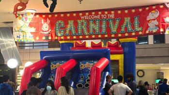 prizes hanging from the met ceiling, with students eating cotton candy in front of inflatable carnival games