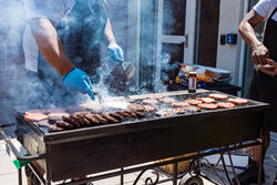 chef grilling burgers on a grill outside