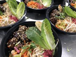 black bowls with lettuce, noodles, and meatballs
